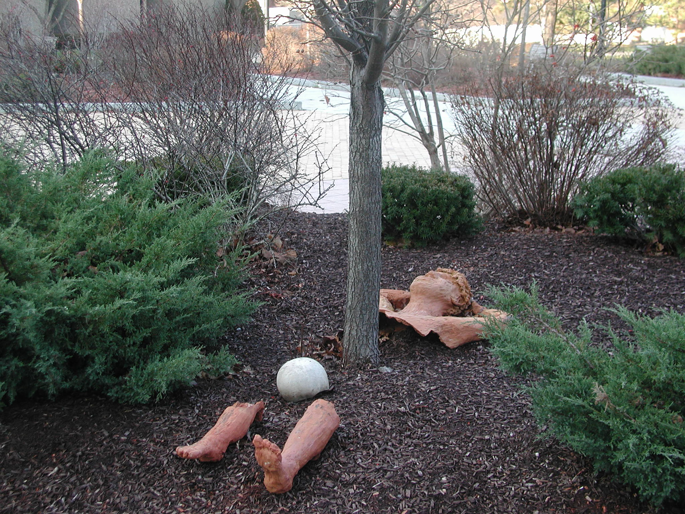 Sculpture of human reclining under tree and half underground